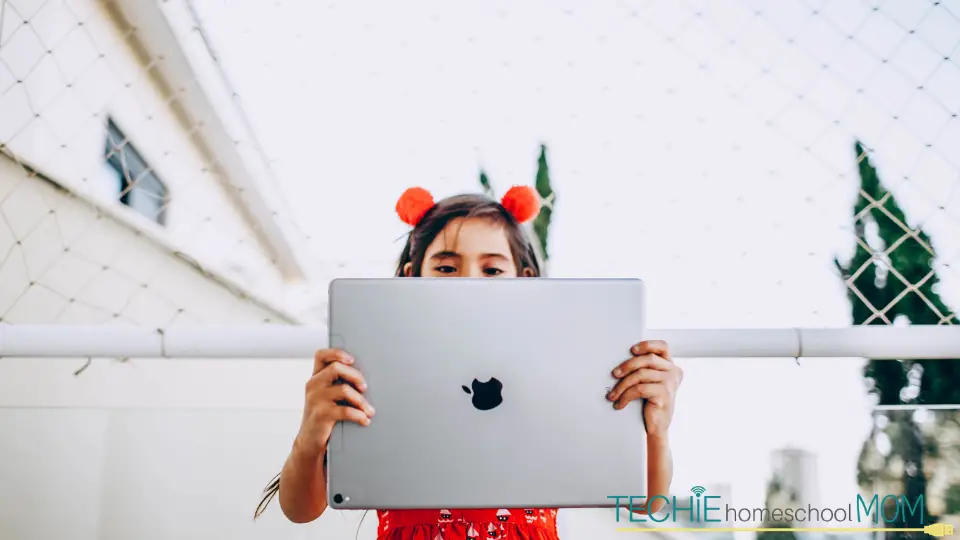 A little girl holding an Ipad to record a video.